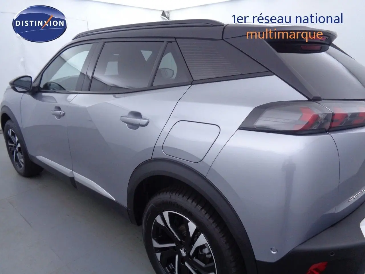 Vue 3/4 arrière droite d'un Peugeot 2008 gris Artense métal avec toit noir et jantes noires biton.