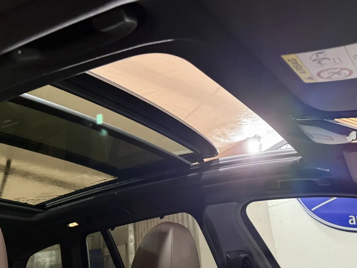 Toit ouvrant panoramique ouvert montrant l'intérieur noir d'un BMW X3 bleu 2023 côté gauche.