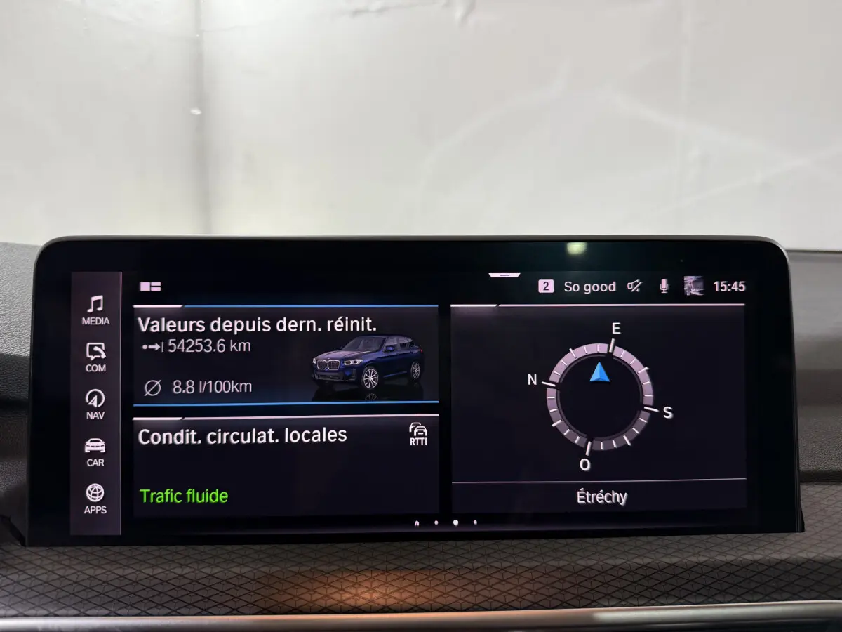 Écran tactile central du tableau de bord montrant les infos de consommation et navigation d'un BMW X3 bleu.