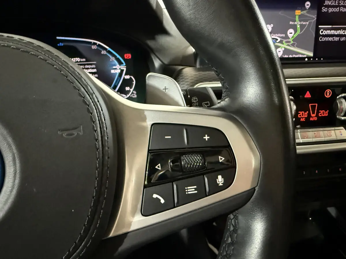 Gros plan sur les commandes au volant côté droit du BMW X3 bleu 2023 avec affichage digital et écran tactile.