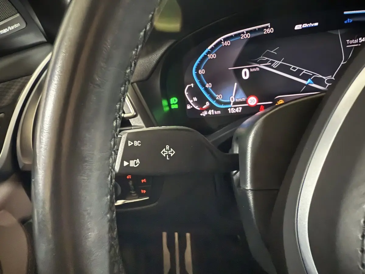 Gros plan sur le tableau de bord numérique et le volant cuir noir du BMW X3 xDrive30e bleu, affichage 12,3 pouces visible.