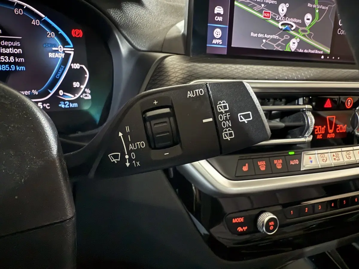 Gros plan sur la commande d’essuie-glace et le tableau de bord numérique du BMW X3 xDrive30e bleu 2023 M Sport.