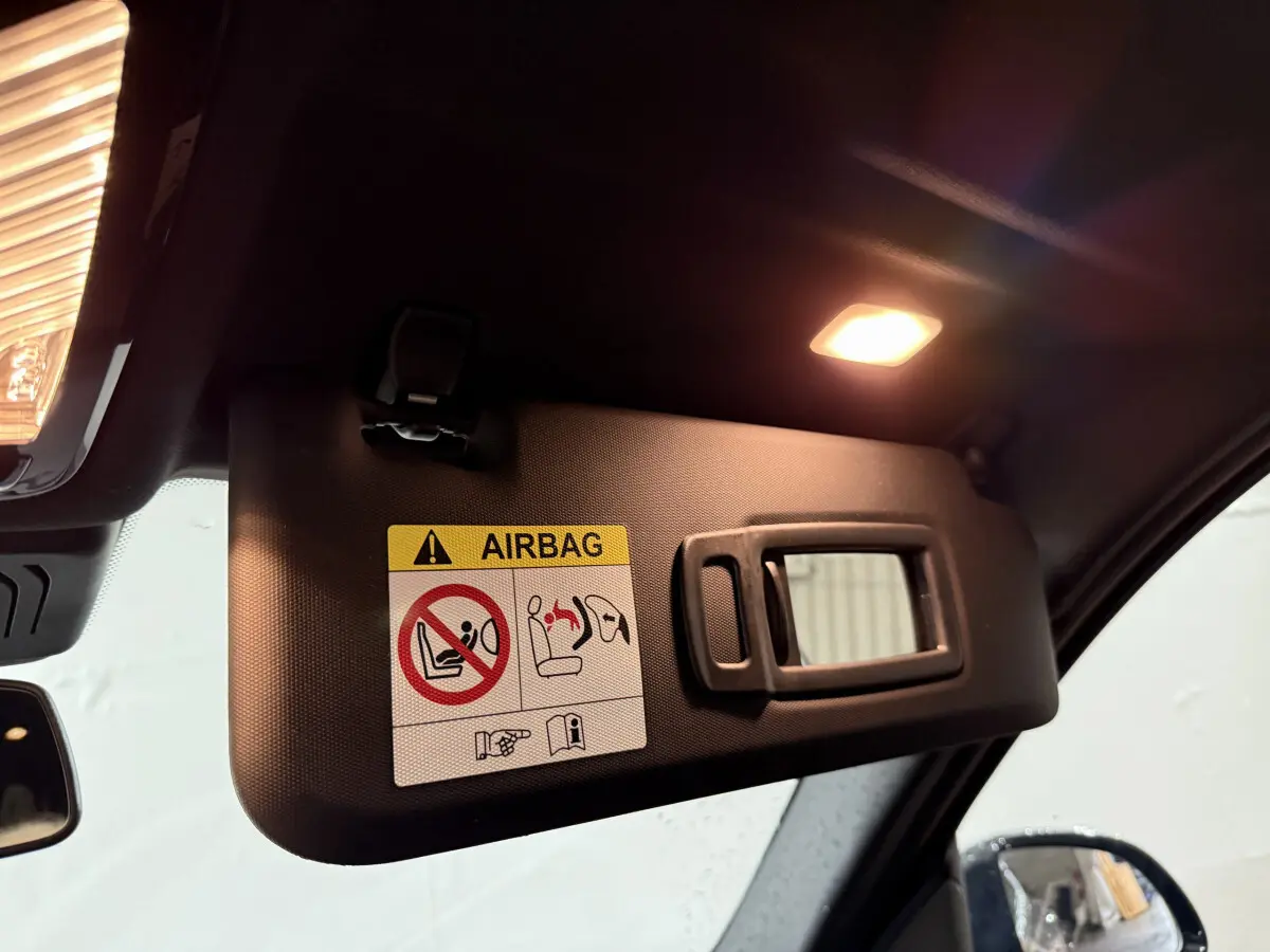Détail du pare-soleil côté conducteur avec avertissement airbag dans le BMW X3 xDrive30e bleu 2023.