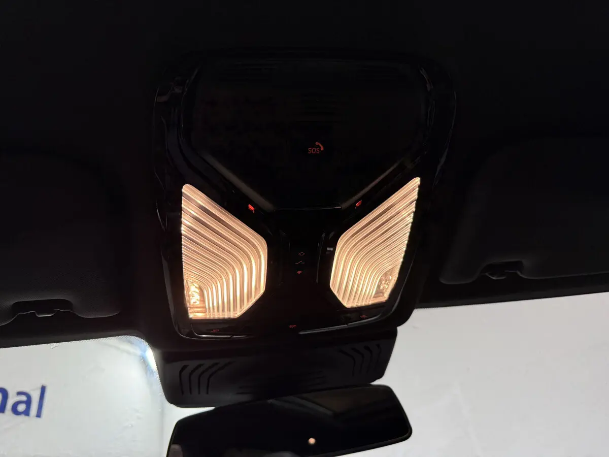 Plafonnier intérieur éclairé avec bouton SOS rouge, vue depuis l'habitacle du BMW X3 xDrive30e bleu 2023.