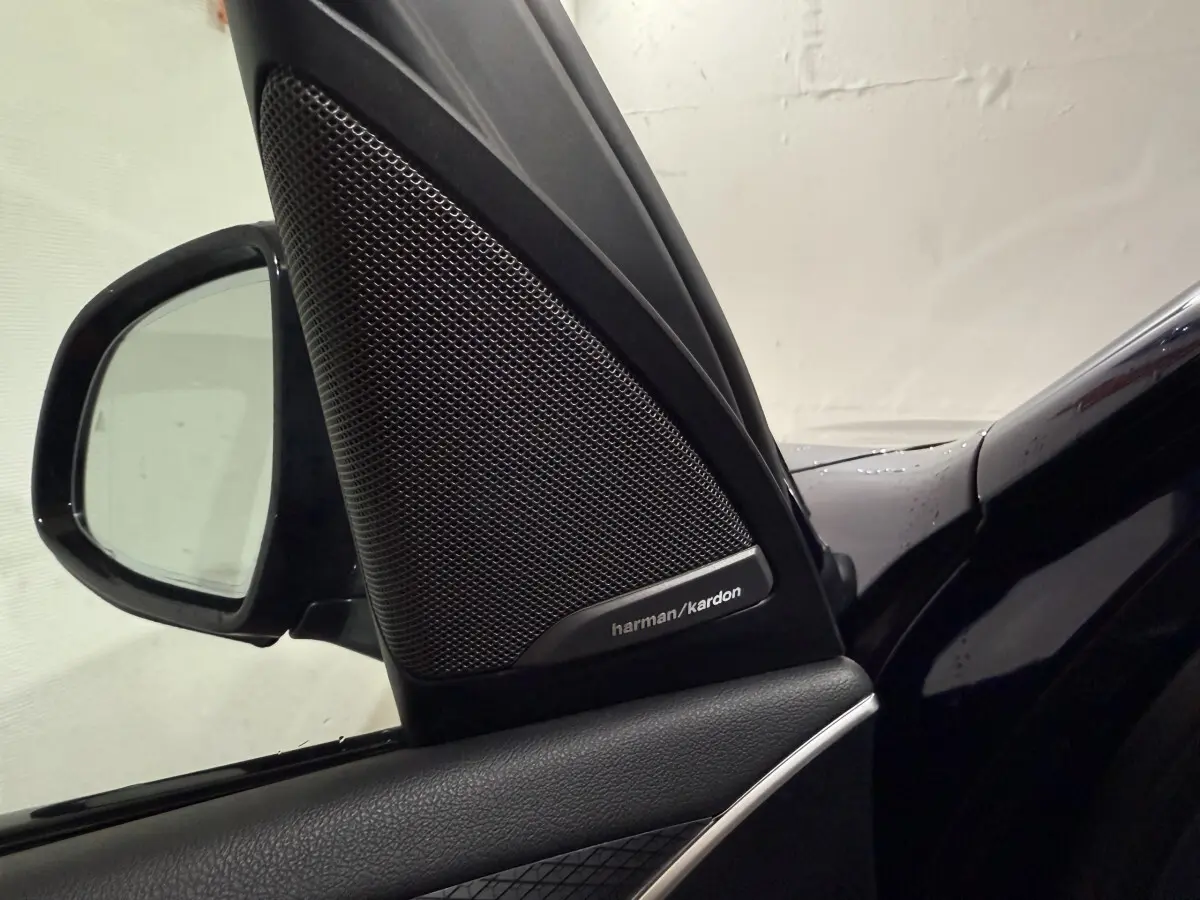 Gros plan sur l'enceinte Harman/Kardon et le rétroviseur côté gauche d'une BMW X3 bleu foncé 2023.