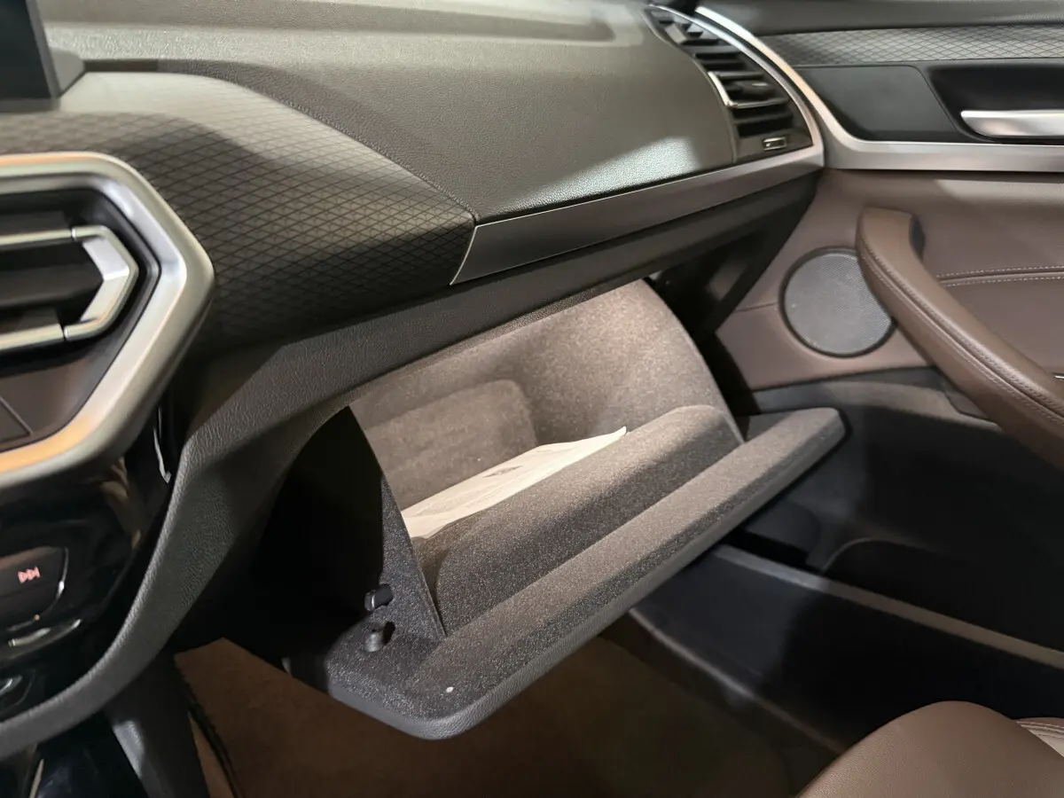 Vue intérieure côté passager du BMW X3 xDrive30e 2023, boîte à gants ouverte et garniture marron visible