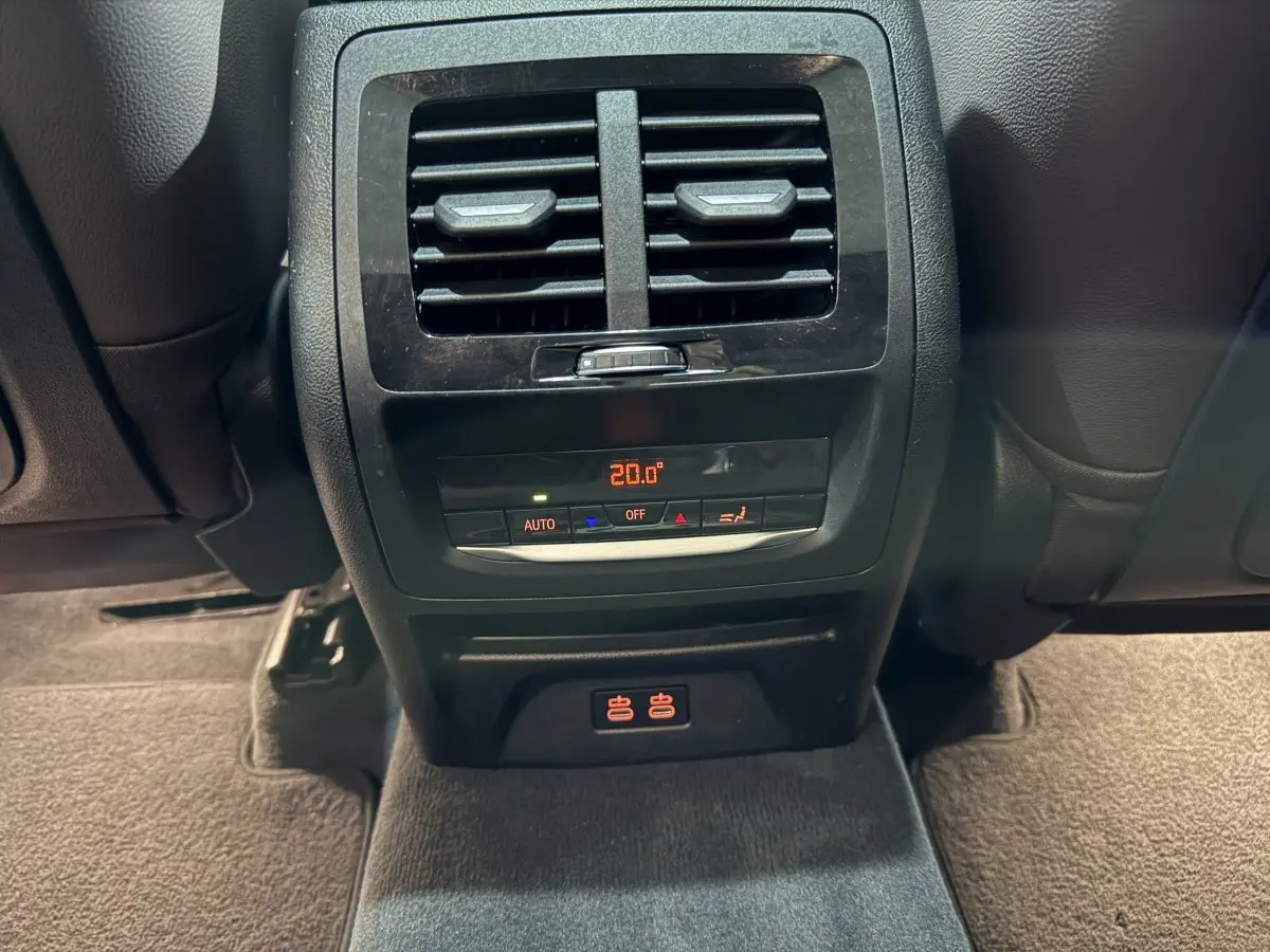 Détail de la console arrière noire du BMW X3 xDrive30e 2023 avec ventilation et commandes climatisation à 20°C.