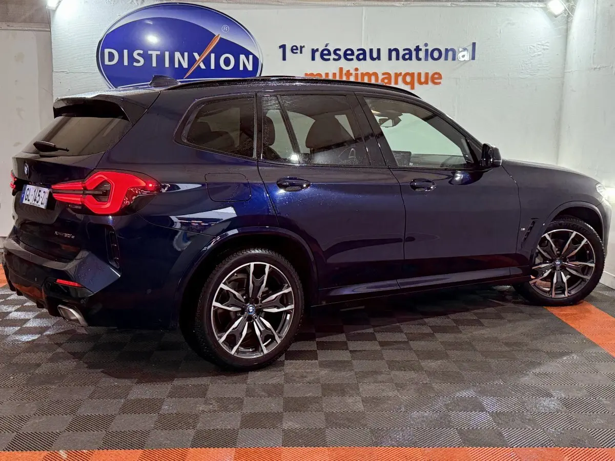BMW X3 xDrive30e bleu en vue latérale droite, avec feux arrière LED et jantes sport M noir et argent.