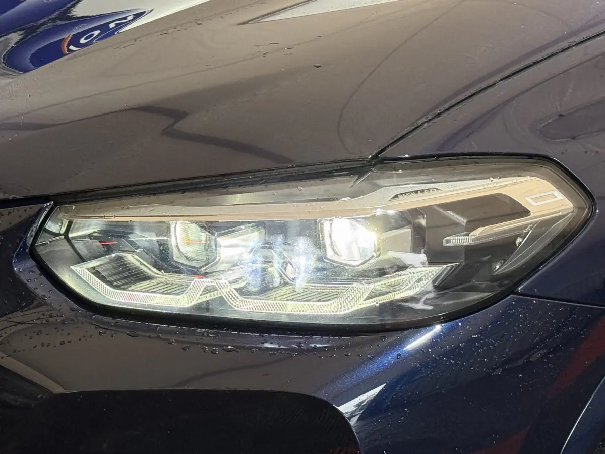 Gros plan sur le phare avant droit d'un BMW X3 xDrive30e bleu, mettant en valeur ses LED et détails modernes.