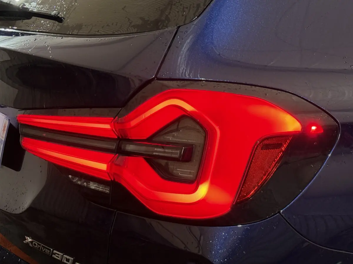 Gros plan sur le feu arrière droit rouge vif du BMW X3 xDrive30e bleu 2023, soulignant son design lumineux distinctif.