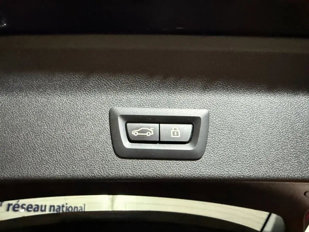 Boutons d'ouverture et de verrouillage du coffre sur le panneau intérieur d'un BMW X3 bleu hybride rechargeable.