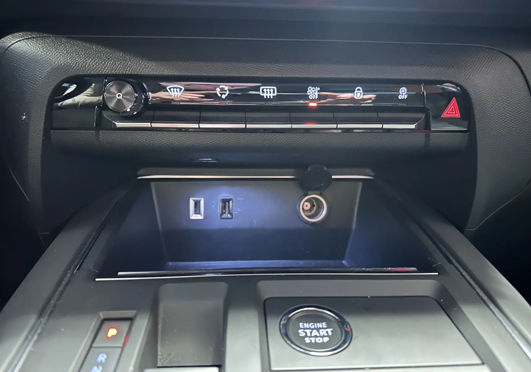Vue rapprochée de la console centrale du Citroën C5 Aircross hybride noir 2025, avec boutons de contrôle, ports USB et bouton start/stop.