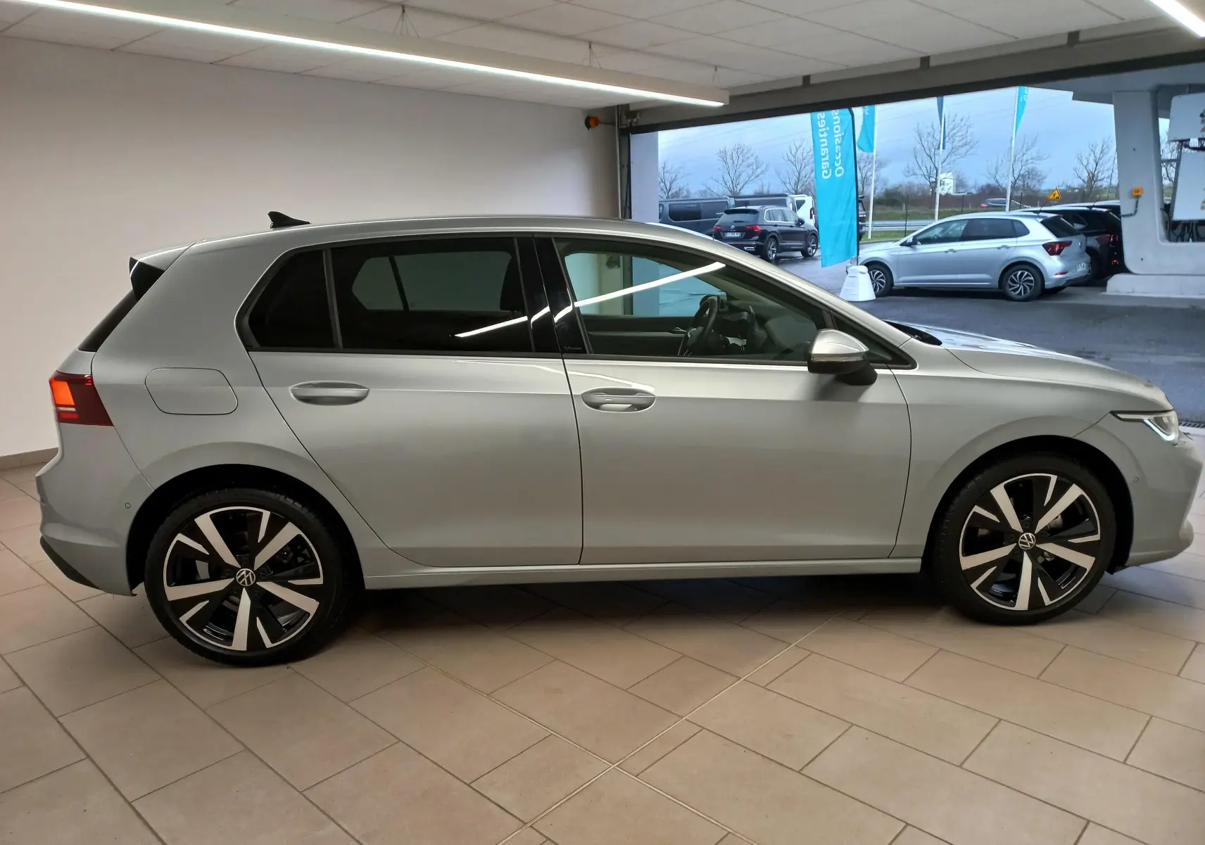 Profil latéral droit d'une Volkswagen Golf 1.5 eTSI 116 BVM6 VW Edition en argent Dolomite avec jantes alliage 18 pouces Catania.