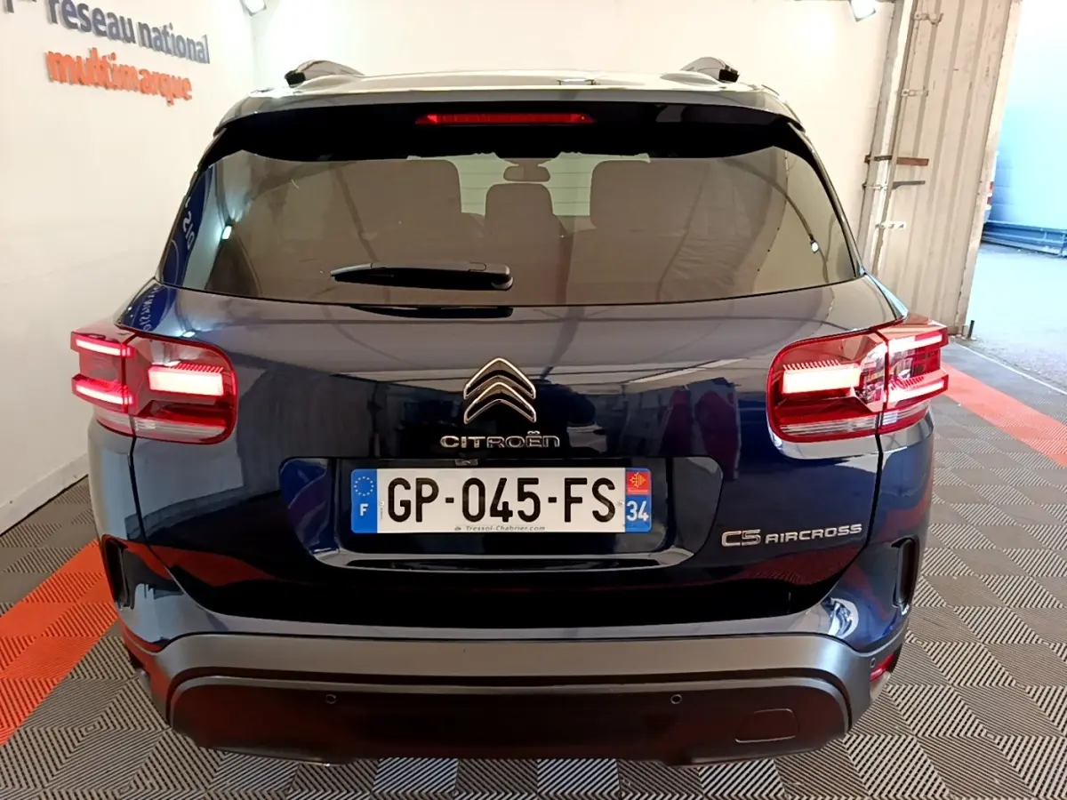 Vue arrière d'un Citroën C5 Aircross bleu foncé avec feux allumés, immatriculé en France, en intérieur.