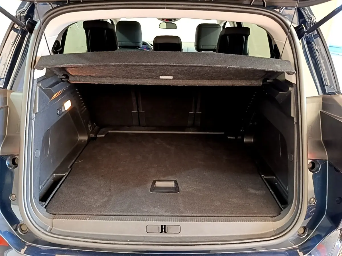 Coffre ouvert arrière d’un Citroën C5 Aircross 2023 bleu foncé avec tablette cache-bagages et sièges noirs visibles.