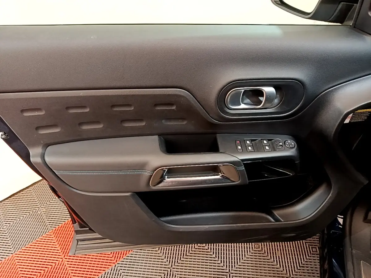 Vue intérieure du panneau de porte avant gauche du Citroën C5 Aircross 2023, avec commandes électriques et poignée chromée.