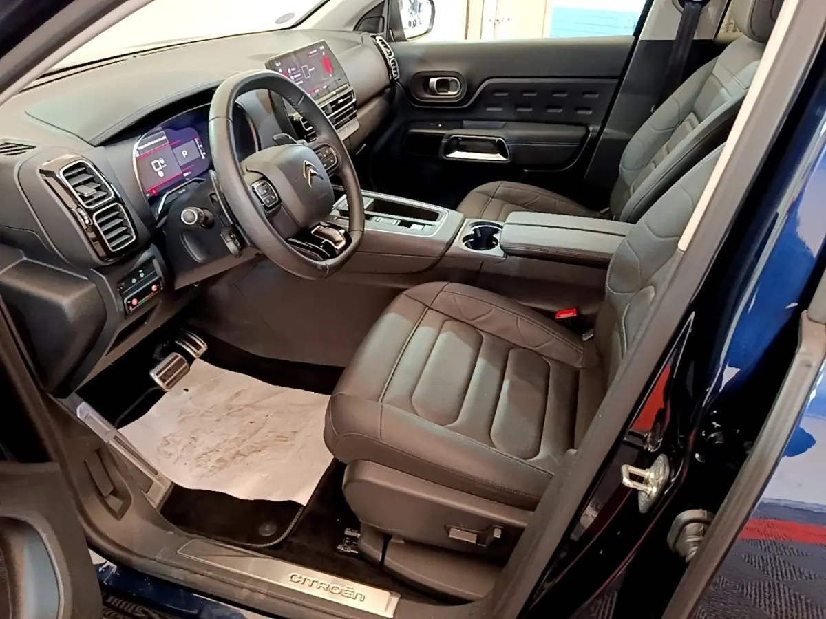 Intérieur avant droit du Citroën C5 Aircross 2023 bleu, avec sièges cuir noirs et tableau de bord digital lumineux.