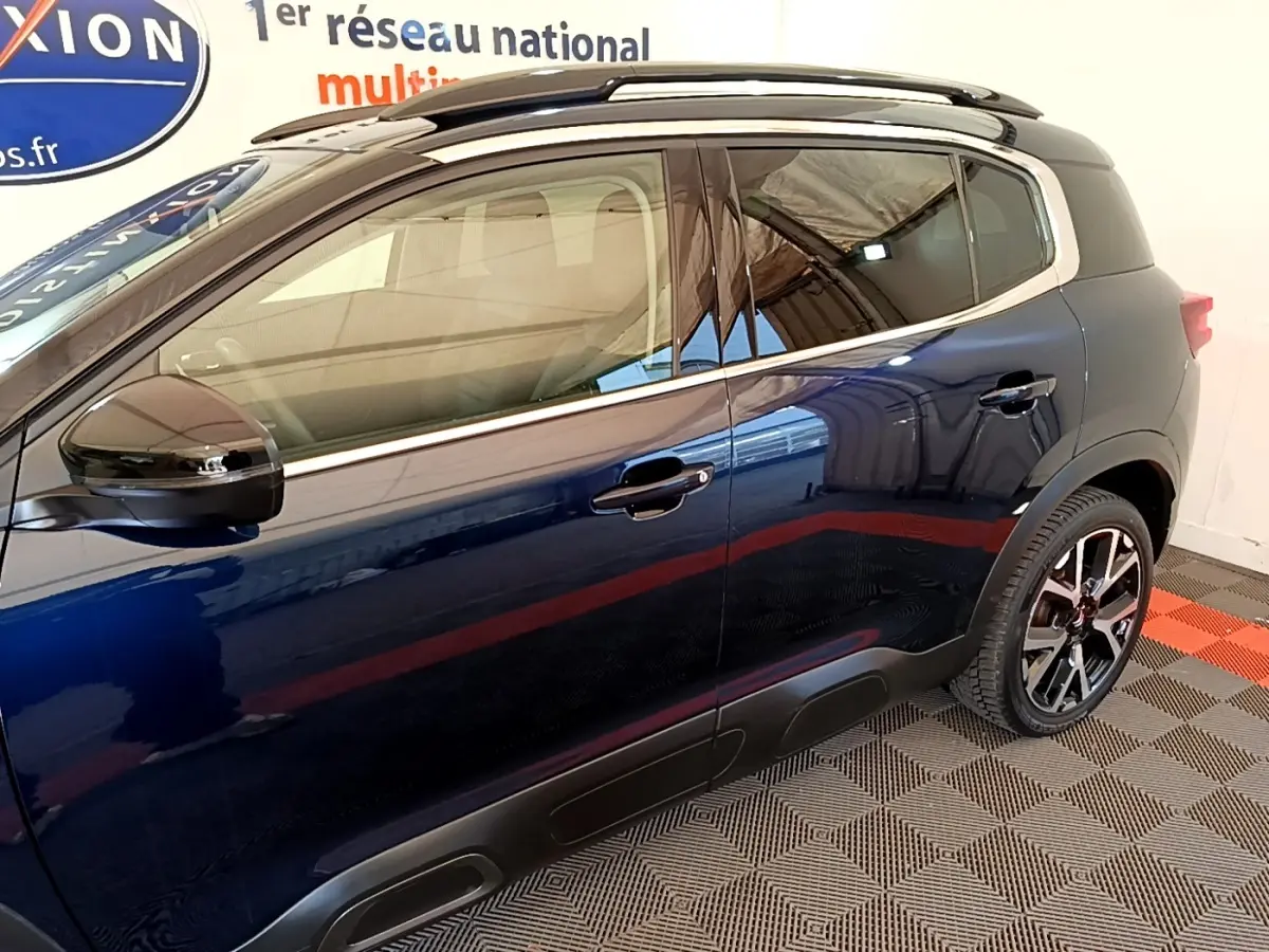 Vue côté droit du Citroën C5 Aircross 2023 bleu foncé avec jantes alliage et barres de toit noires.