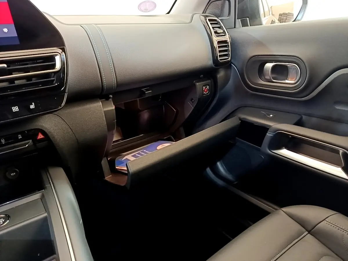 Vue intérieure côté passager du tableau de bord noir avec boîte à gants ouverte et coutures bleues sur Citroën C5 Aircross 2023.