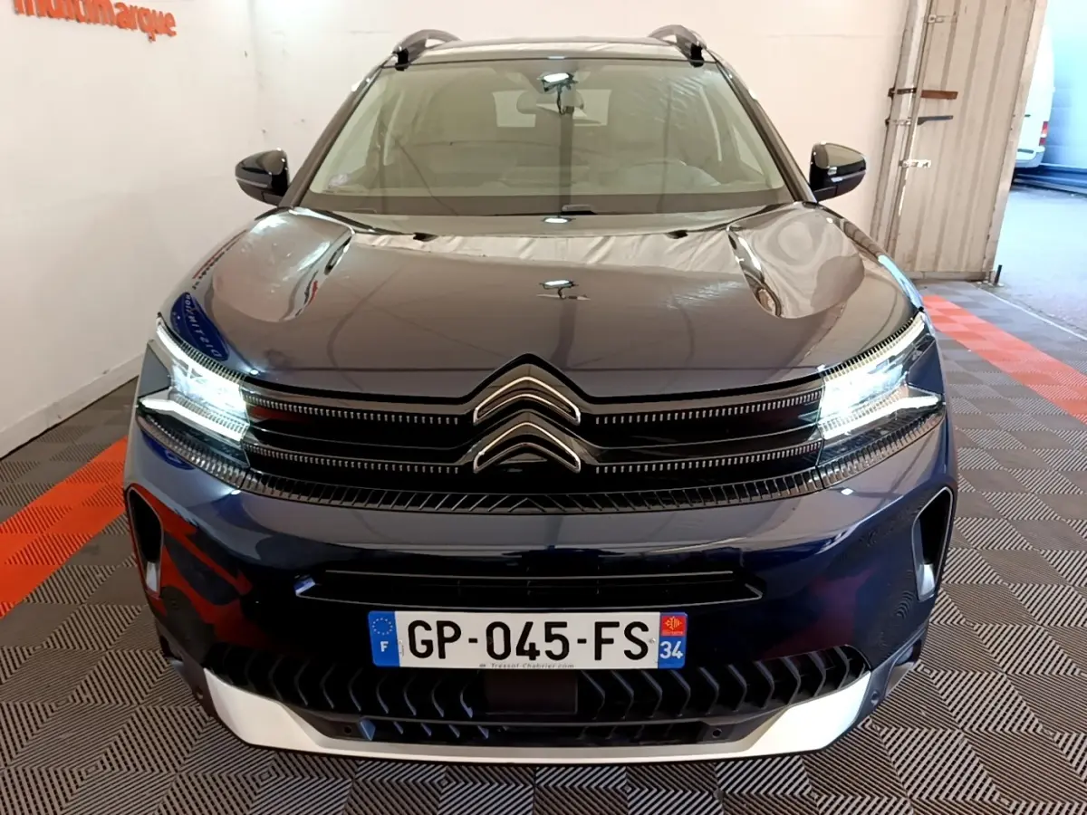 Vue avant d'un Citroën C5 Aircross 2023 bleu foncé avec feux LED allumés et calandre distinctive double chevron.