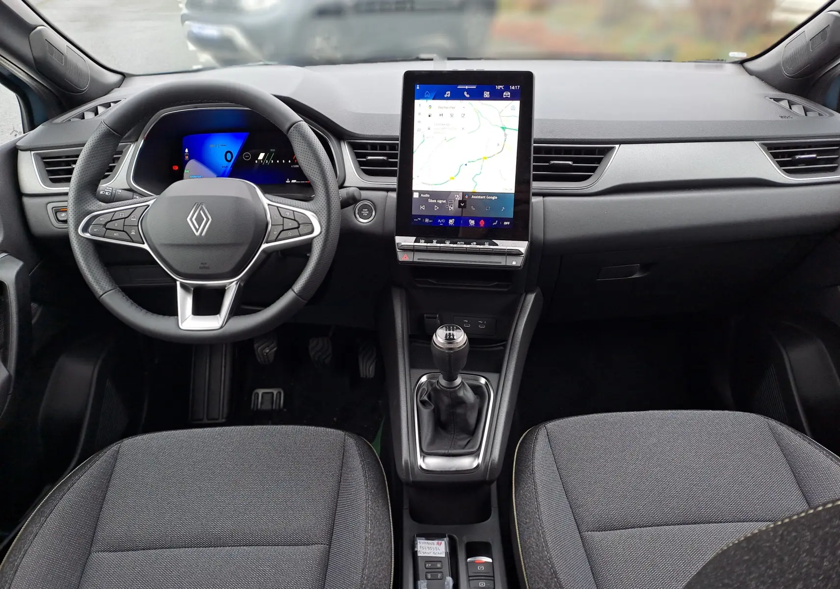 Vue intérieure avant du Renault Symbioz 2025, tableau de bord noir avec écran tactile vertical et levier de vitesses manuel.