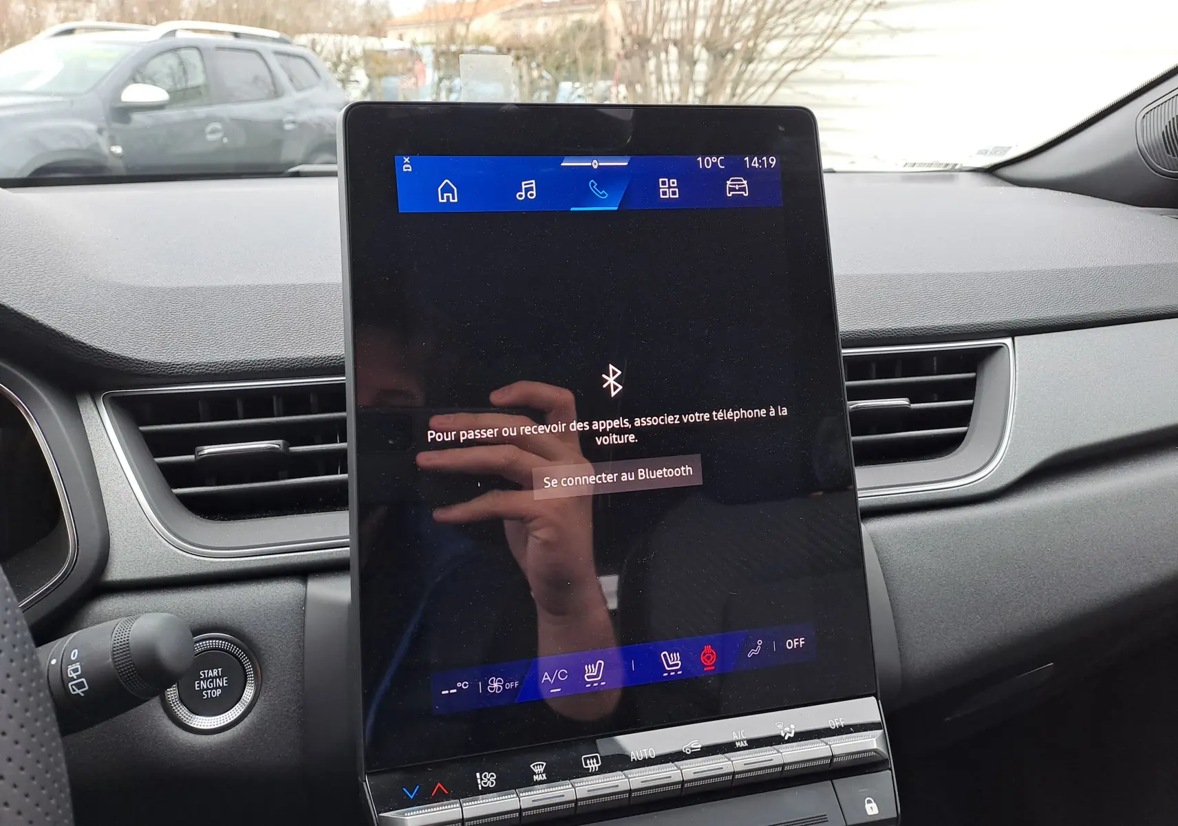 Vue intérieure centrée sur l'écran tactile vertical du tableau de bord du Renault Symbioz bleu Mercure, avec commandes climatisation visibles.