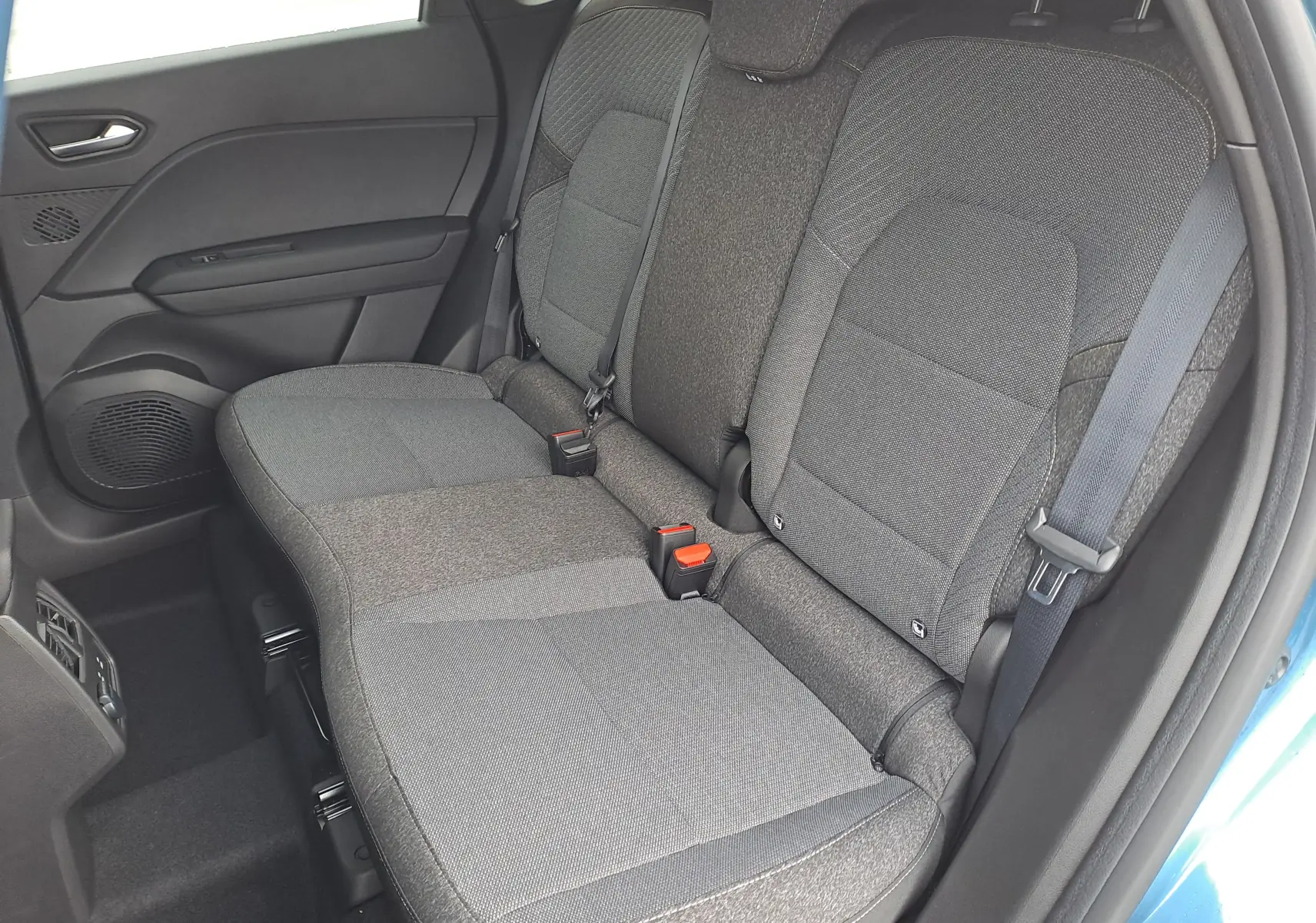 Vue intérieure côté droit sur les sièges arrière gris du Renault Symbioz bleu Mercure, montrant les ceintures et la porte ouverte.