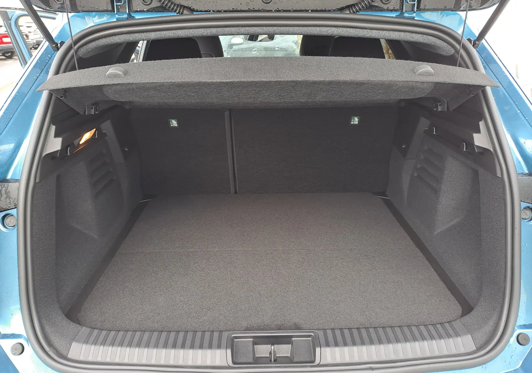 Vue arrière du coffre ouvert du Renault Symbioz bleu mercure, montrant un espace de chargement propre et spacieux.