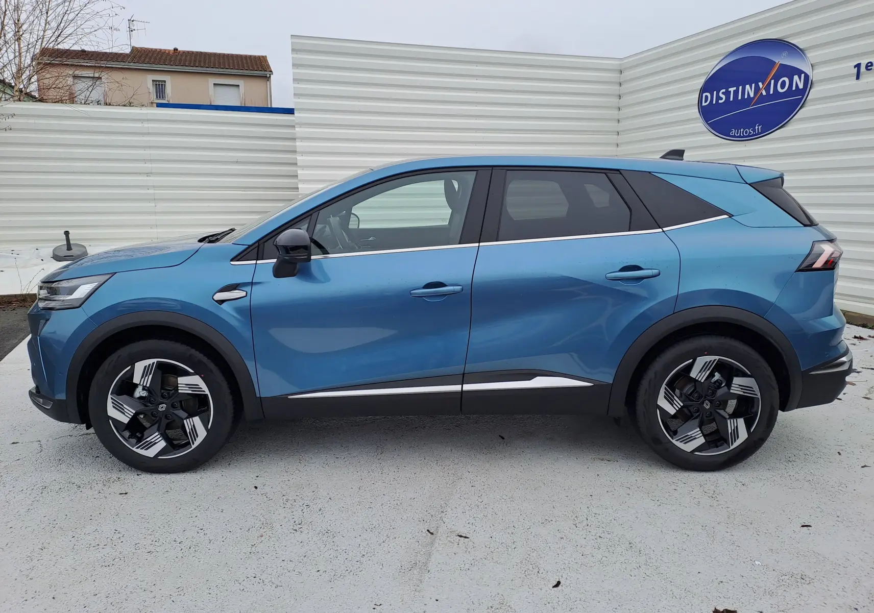 Profil latéral droit d’un Renault Symbioz bleu mercure 2025, avec jantes bicolores et lignes chromées distinctives.