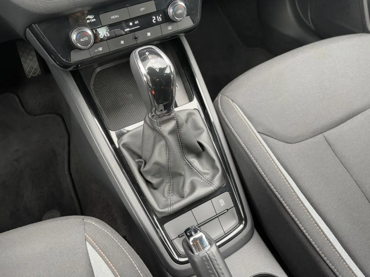 Gros plan sur la console centrale de la Skoda Scala 2024 avec levier de boîte auto et sièges gris à surpiqûres.