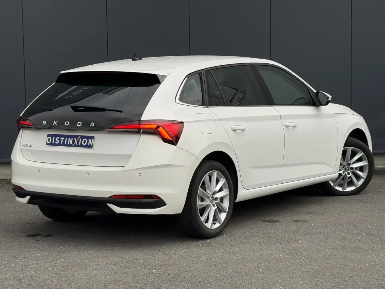 Vue 3/4 arrière droite d'une Skoda Scala blanche Candy avec jantes alliage 17 pouces et vitres teintées.