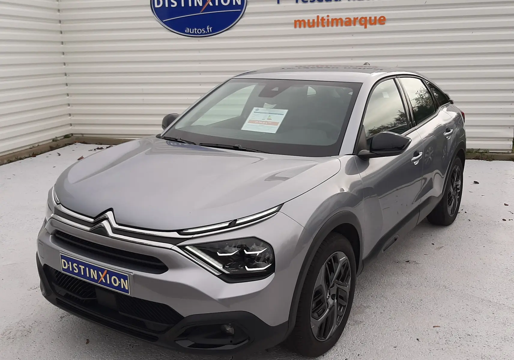 Citroën C4 Hybrid gris acier vue 3/4 avant droit, avec calandre distinctive et jantes bi-ton.