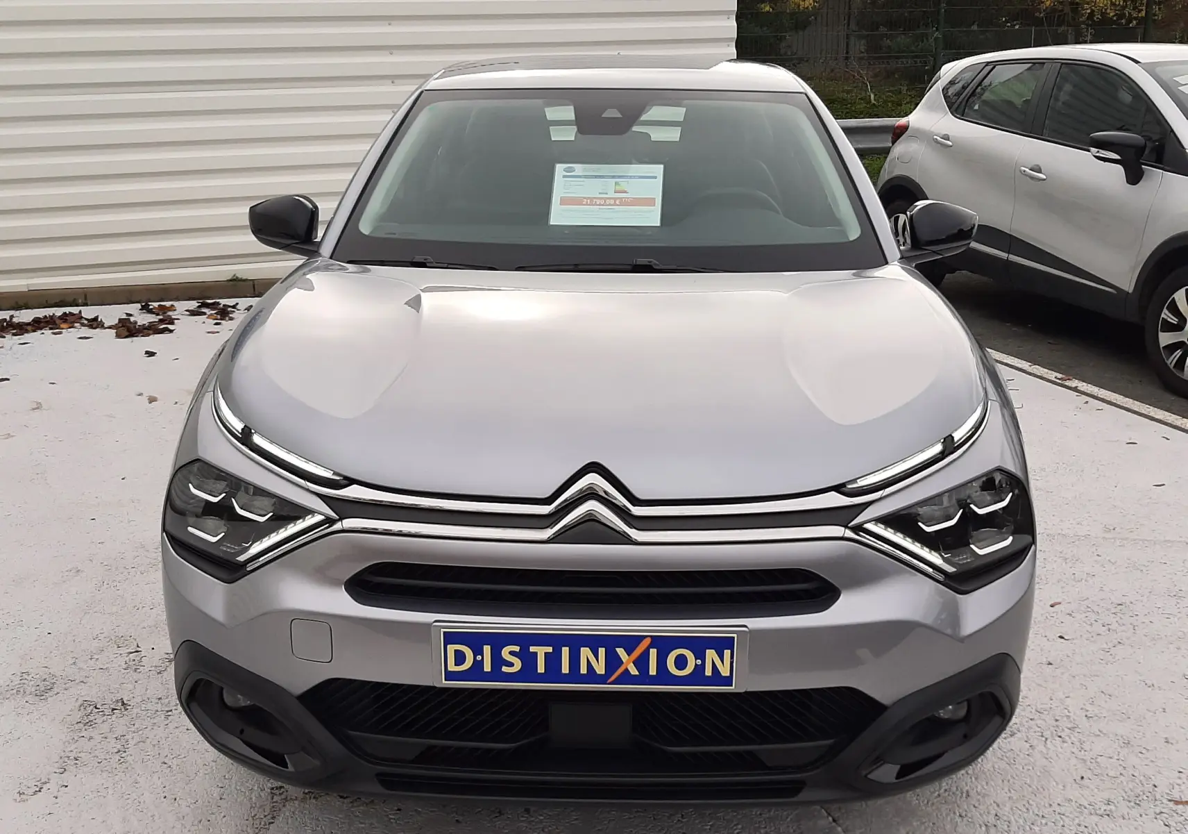 Vue avant d'une Citroën C4 Hybrid 136 gris acier 2024 avec calandre chromée et phares LED distinctifs.