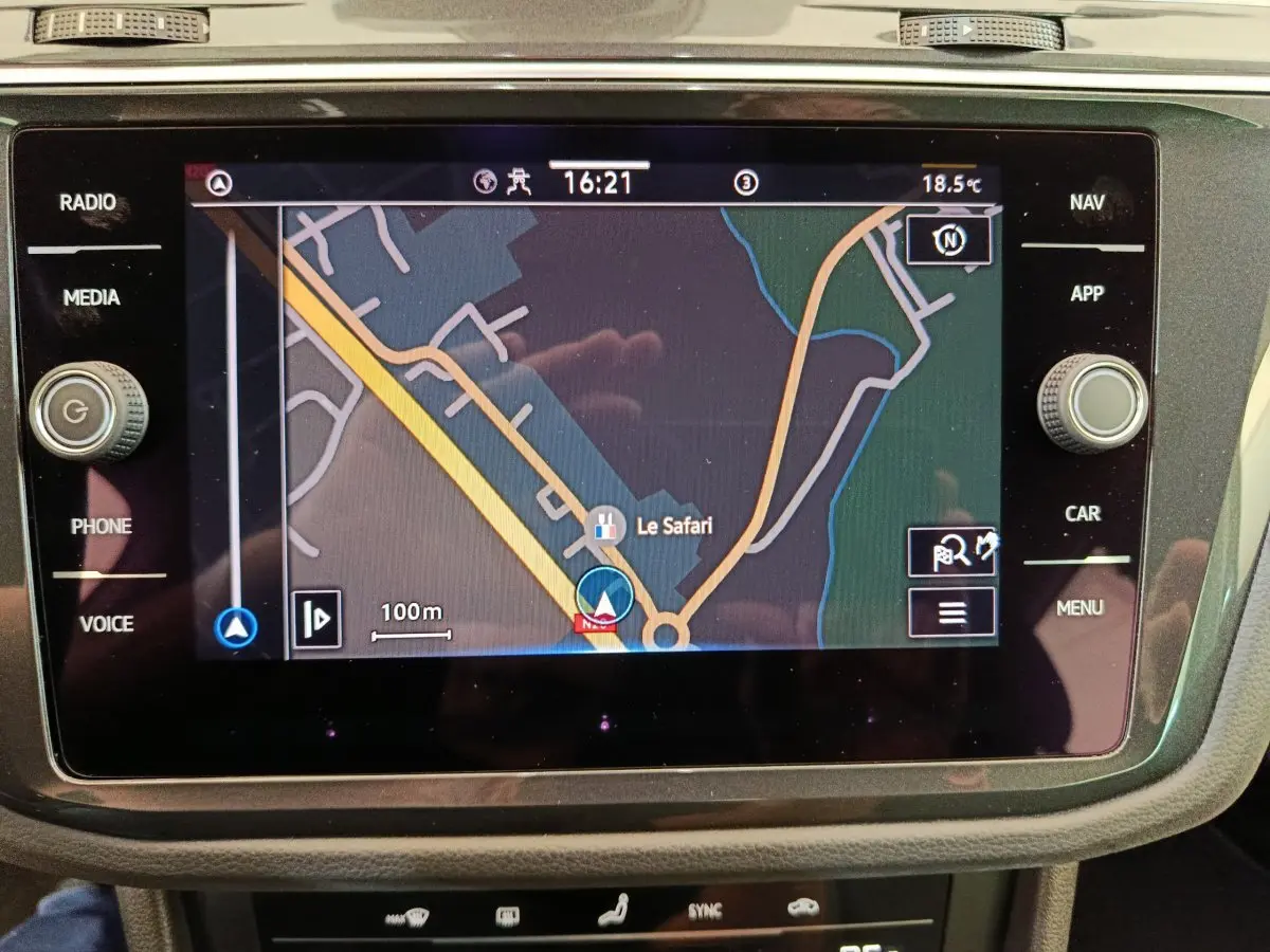Écran tactile central du Volkswagen Tiguan bleu 2022 affichant la navigation GPS avec carte et commandes autour.