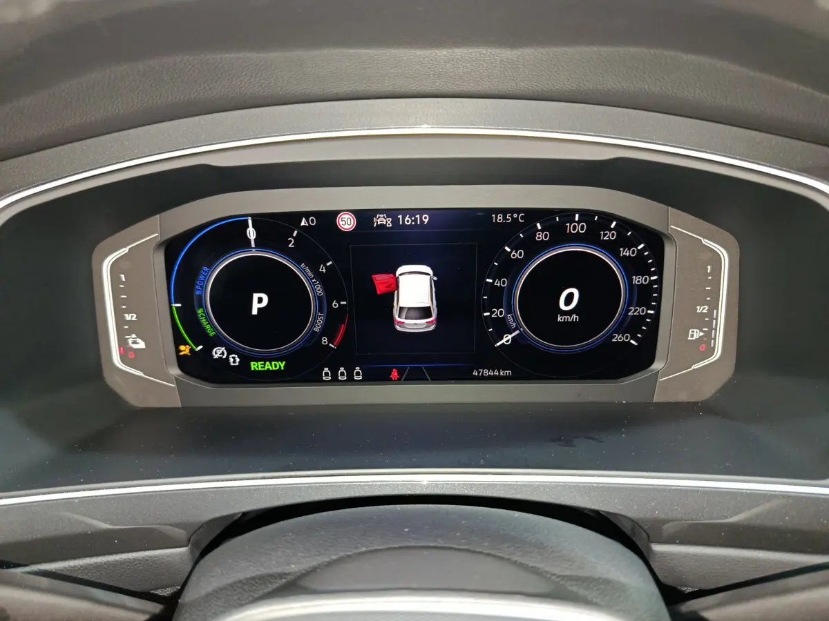 Tableau de bord numérique du Volkswagen Tiguan hybride bleu, affichant la vitesse à 0 km/h et porte avant gauche ouverte.