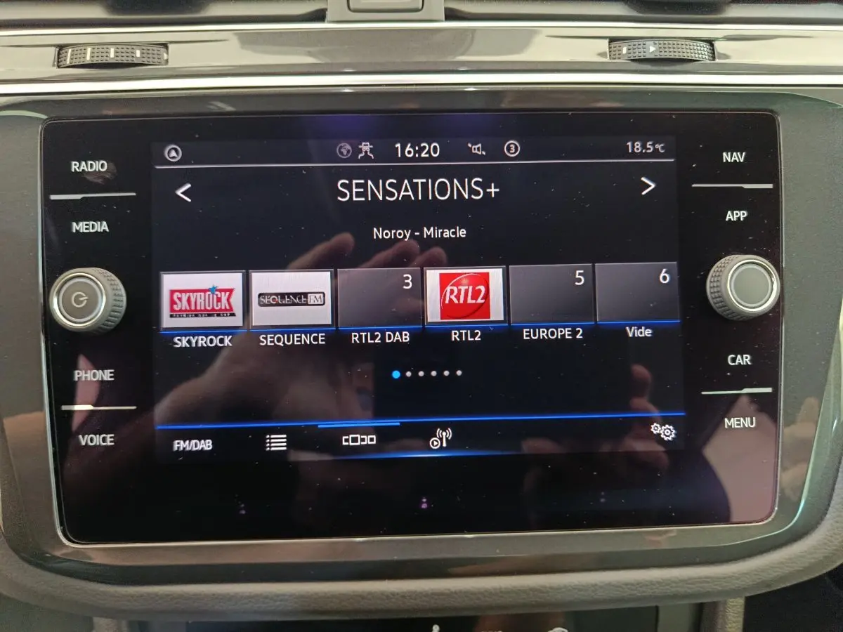 Écran tactile central du Volkswagen Tiguan bleu 2022 affichant la radio avec plusieurs stations FM/DAB visibles.