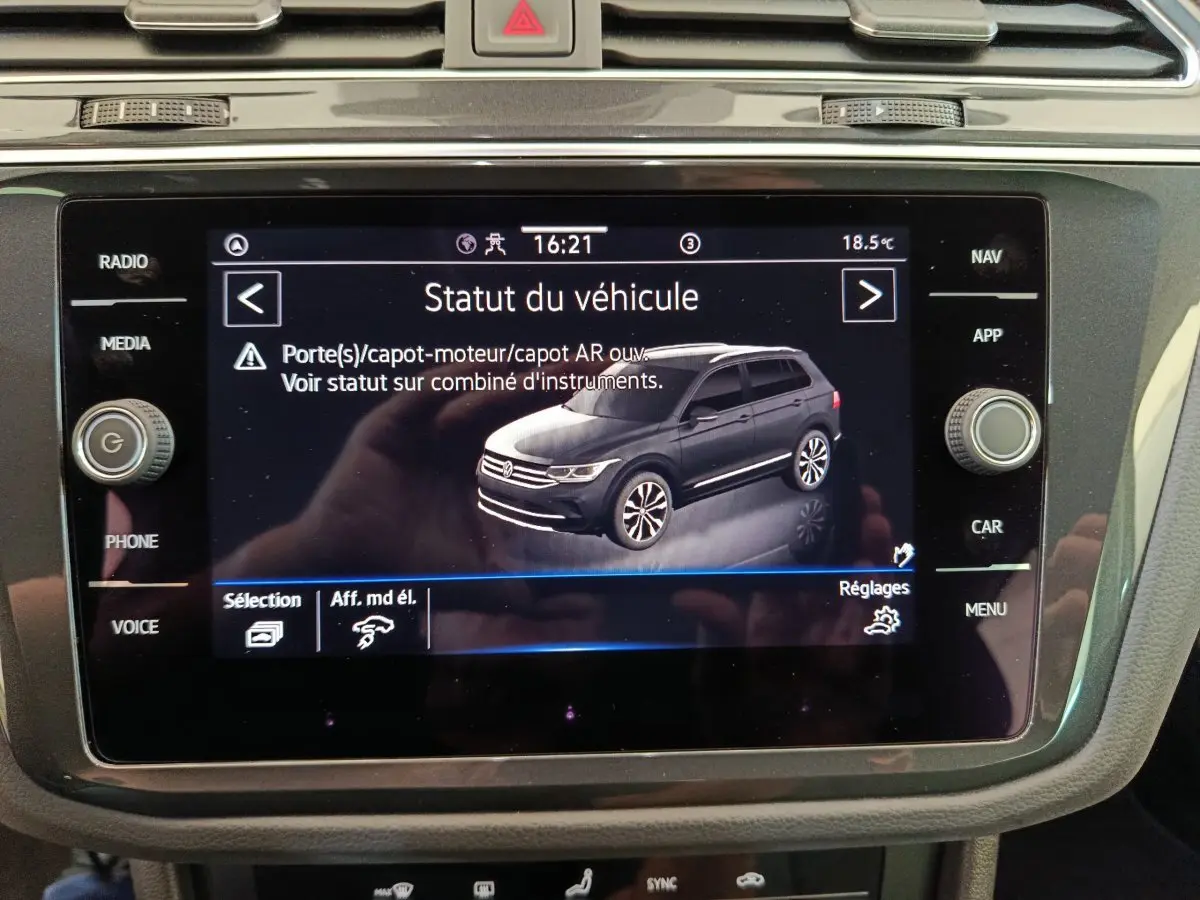 Écran tactile central montrant une vue 3/4 arrière d'un Volkswagen Tiguan bleu foncé sur le tableau de bord