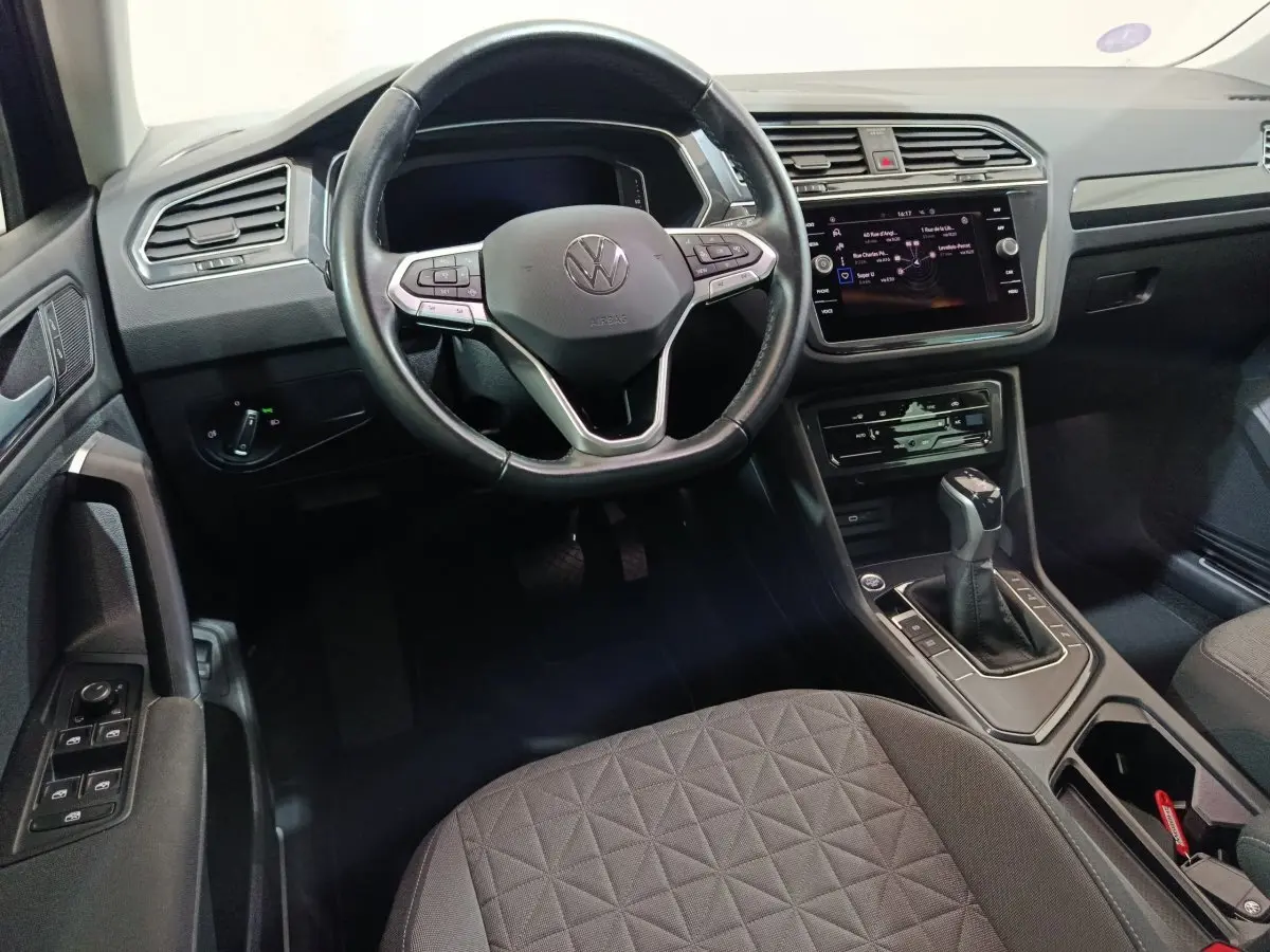 Intérieur noir du Volkswagen Tiguan 2022, vue du poste de conduite avec volant cuir et écran tactile central.