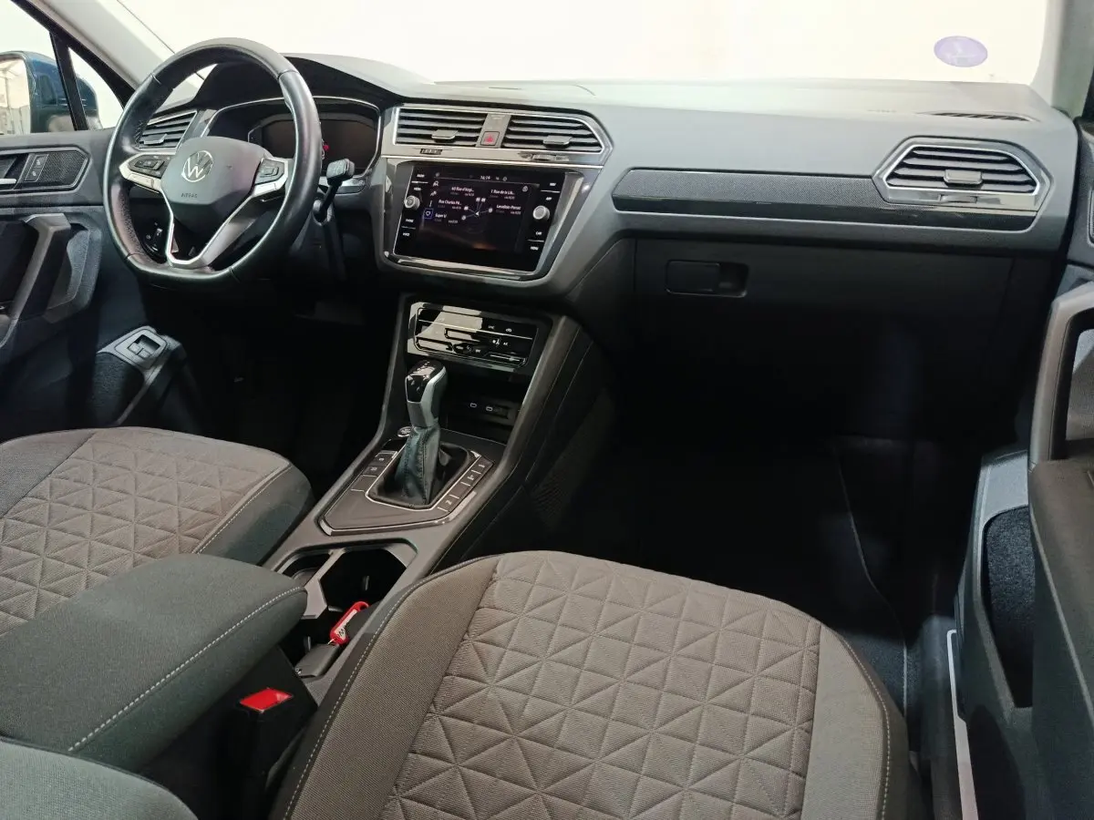 Intérieur avant droit du Volkswagen Tiguan bleu 2022, tableau de bord moderne avec écran tactile et volant multifonctions.