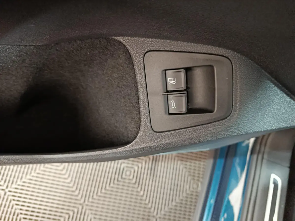 Gros plan sur les commandes d'ouverture du coffre et du bouchon de carburant côté conducteur du Volkswagen Tiguan bleu 2022.