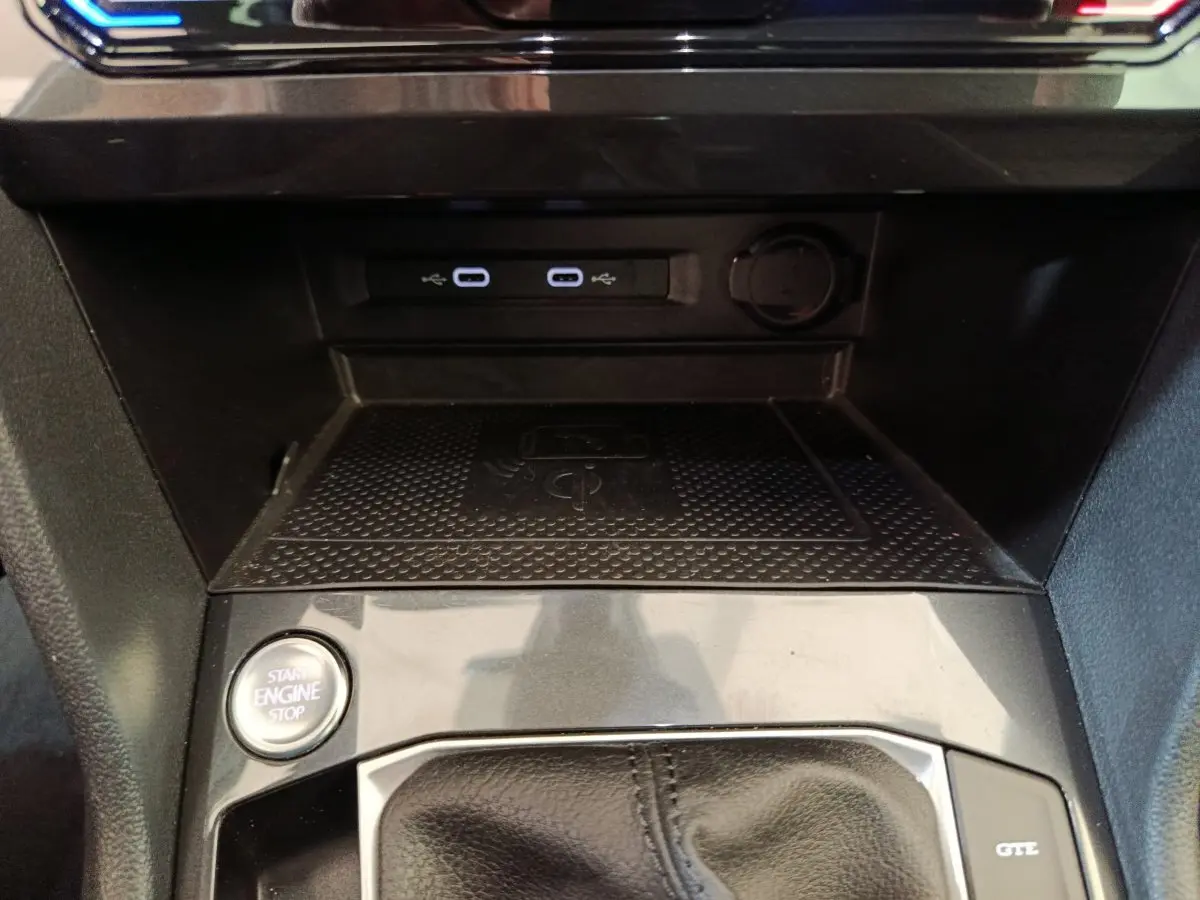 Gros plan sur la console centrale noire du Volkswagen Tiguan avec bouton start/stop et ports USB éclairés.