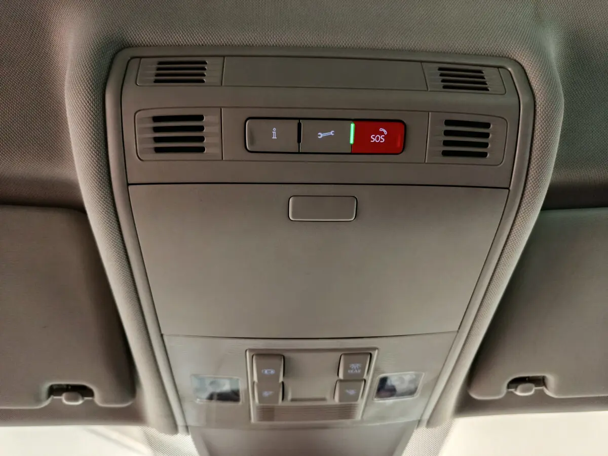 Vue en gros plan du plafonnier gris avec bouton SOS rouge et commandes d'éclairage dans un Volkswagen Tiguan 2022.