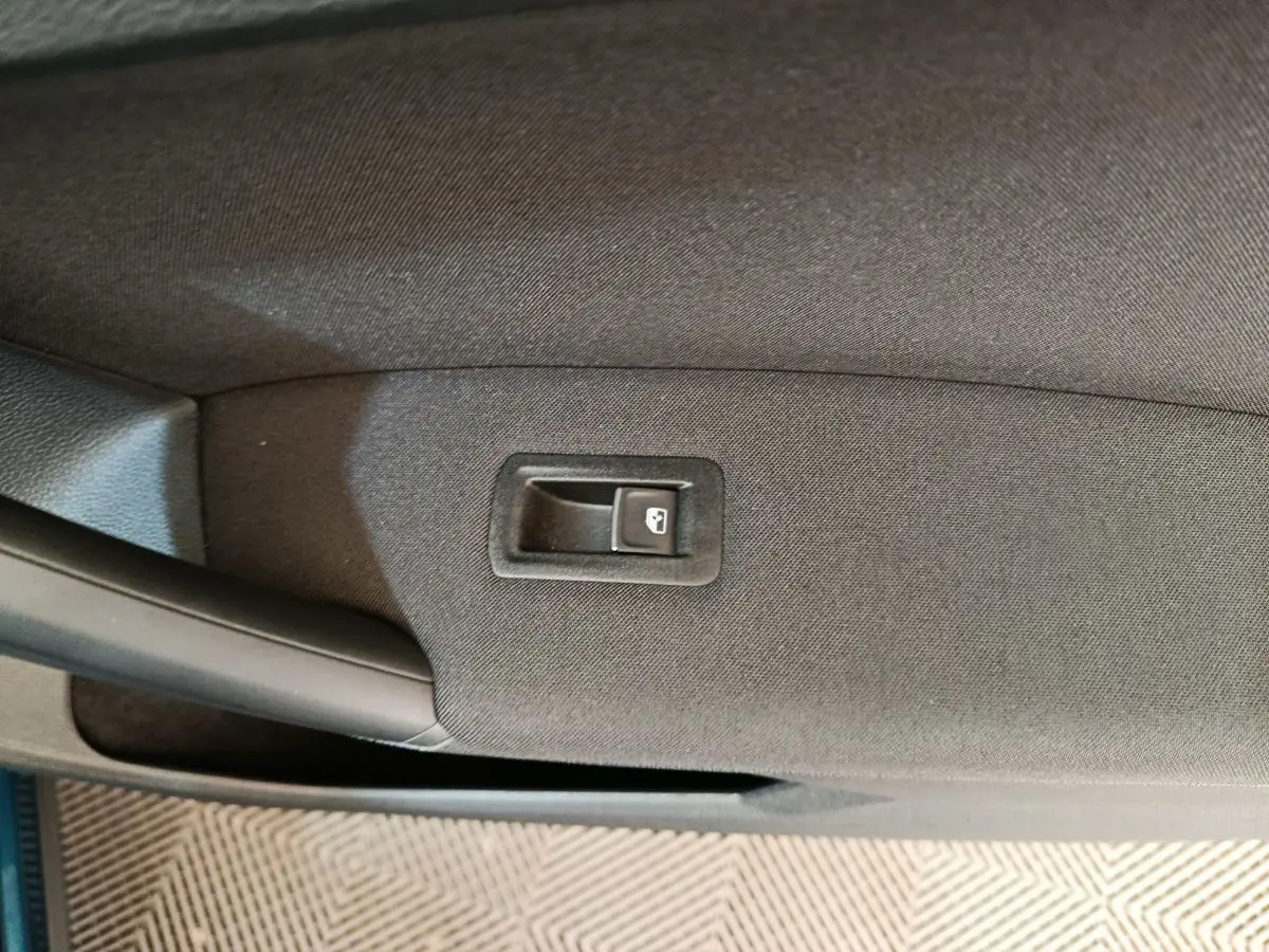 Bouton de verrouillage de porte sur la garniture intérieure noire de la porte côté gauche du Volkswagen Tiguan bleu hybride.