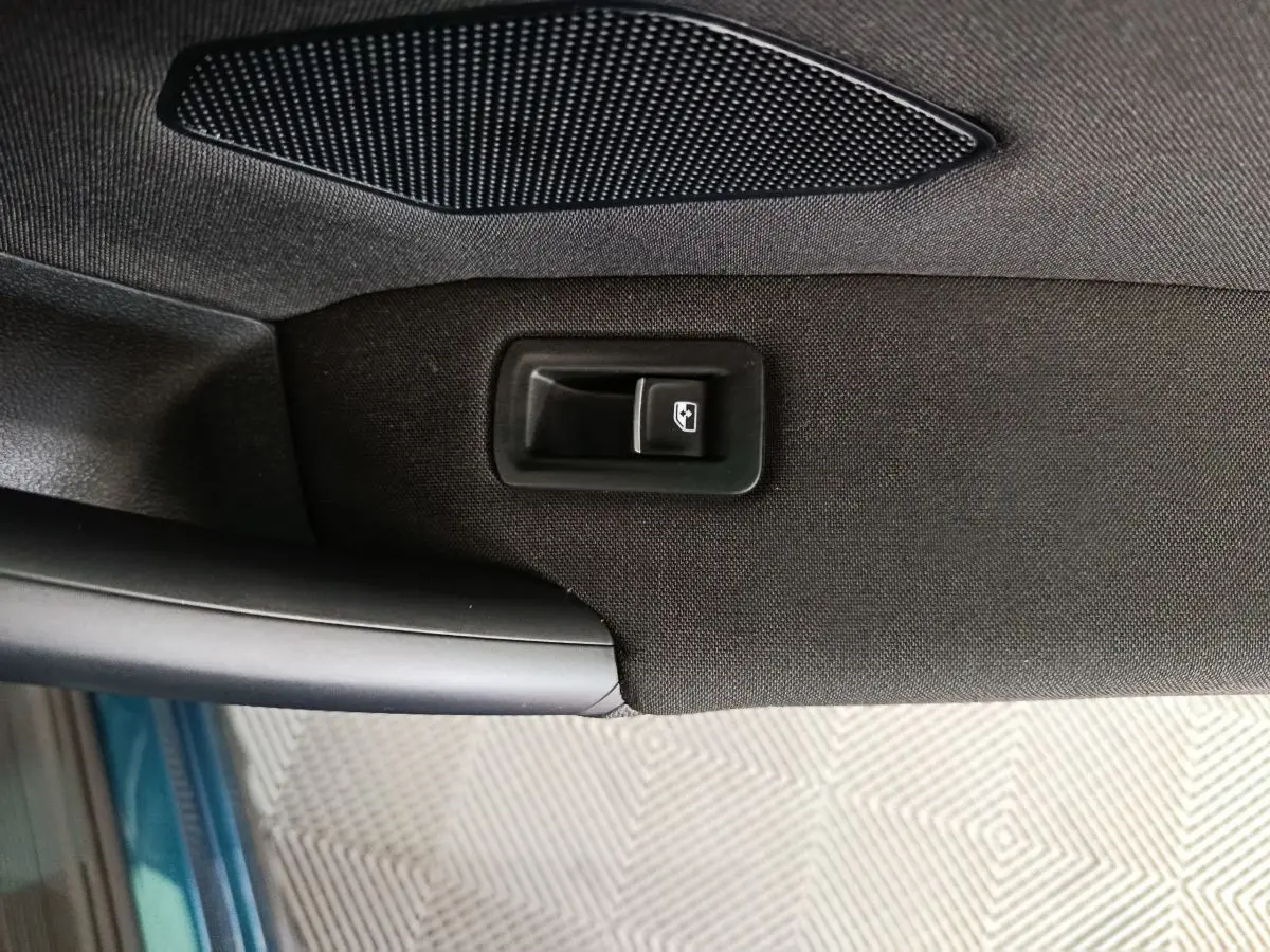 Détail de la commande de lève-vitre sur la portière intérieure côté conducteur du Volkswagen Tiguan bleu 2022.