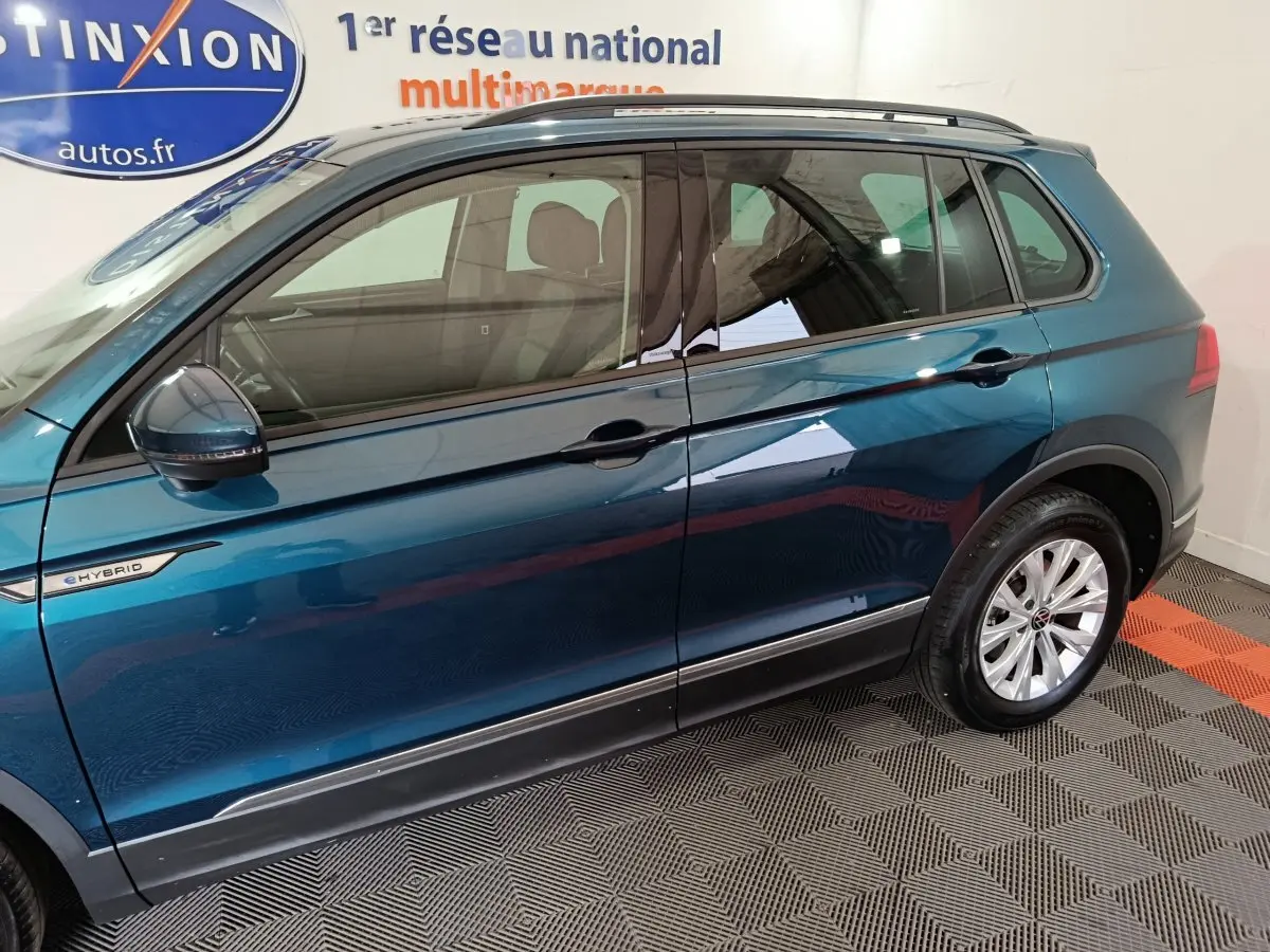 Vue latérale côté gauche du Volkswagen Tiguan bleu hybride rechargeable avec badge eHYBRID et jantes argentées.