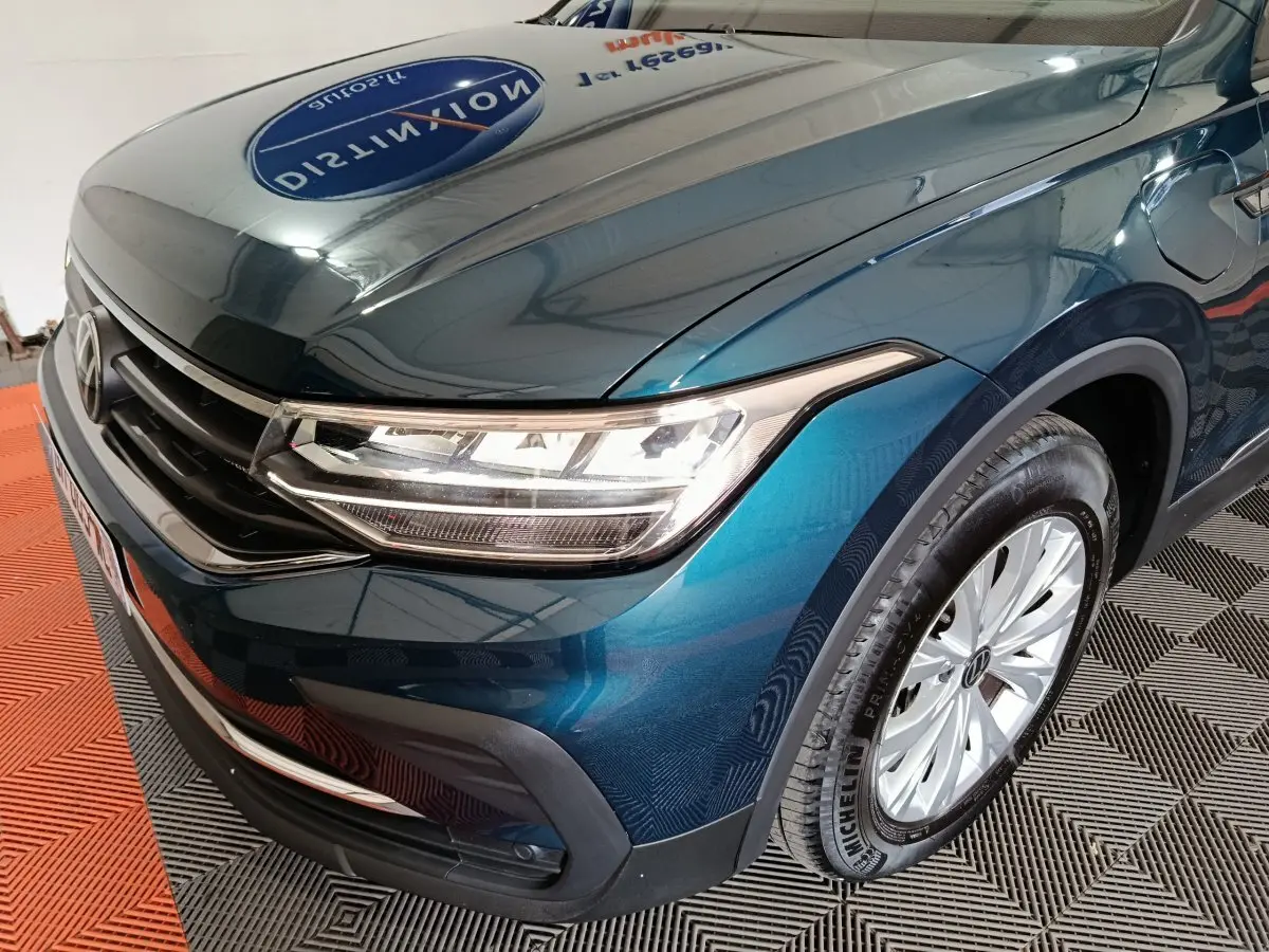 Vue 3/4 avant droit d'un Volkswagen Tiguan bleu avec phares LED et jantes alliage visibles.