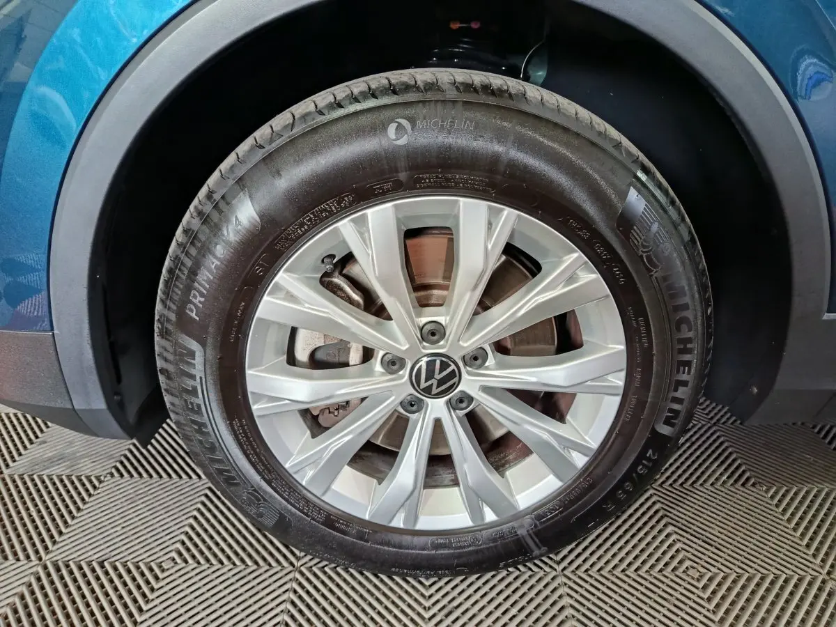 Gros plan sur la roue avant droite d’un Volkswagen Tiguan bleu 2022 avec jante alliage et pneu Michelin.