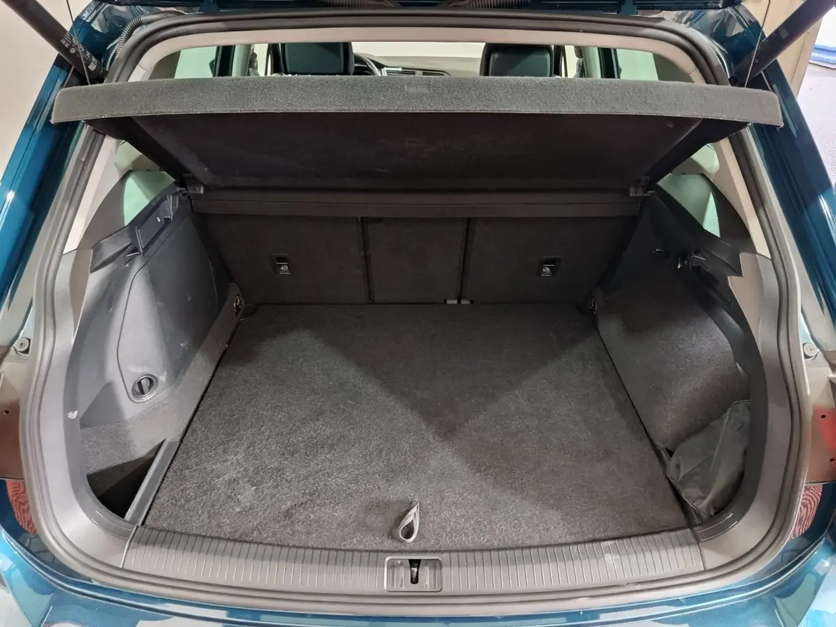 Coffre ouvert en bleu du Volkswagen Tiguan 1.4 eHybrid 245 DSG6, vue arrière montrant l'espace de chargement vide.