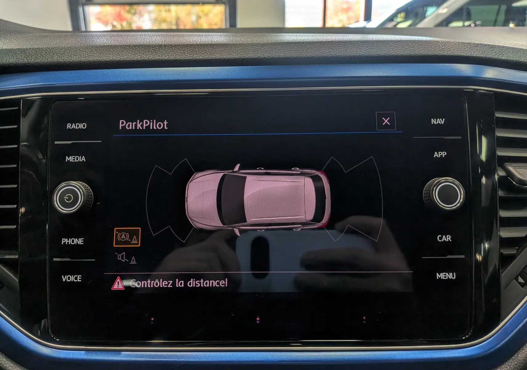 Affichage central du système ParkPilot montrant un Volkswagen T-Roc bleu Ravenna avec toit blanc en vue aérienne.