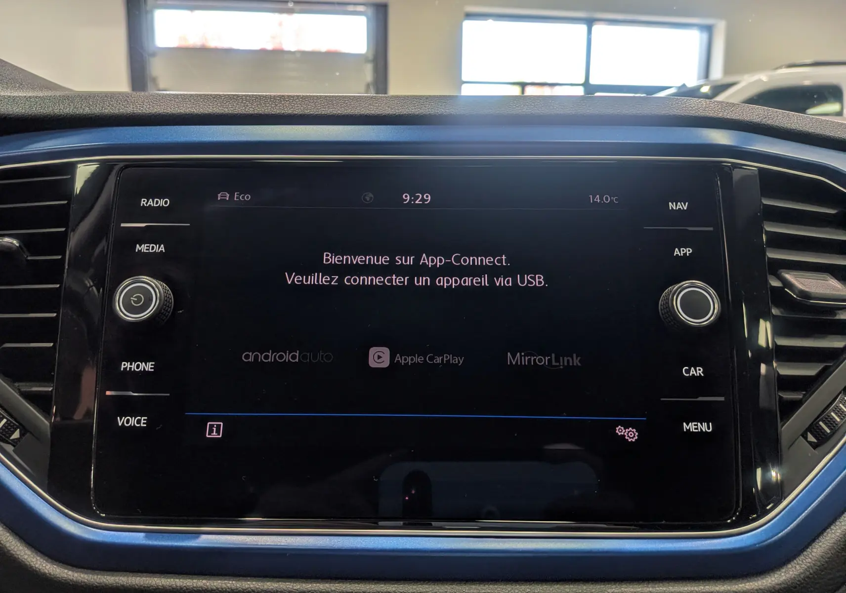 Écran central tactile du Volkswagen T-Roc bleu Ravenna avec interface App-Connect et commandes autour.